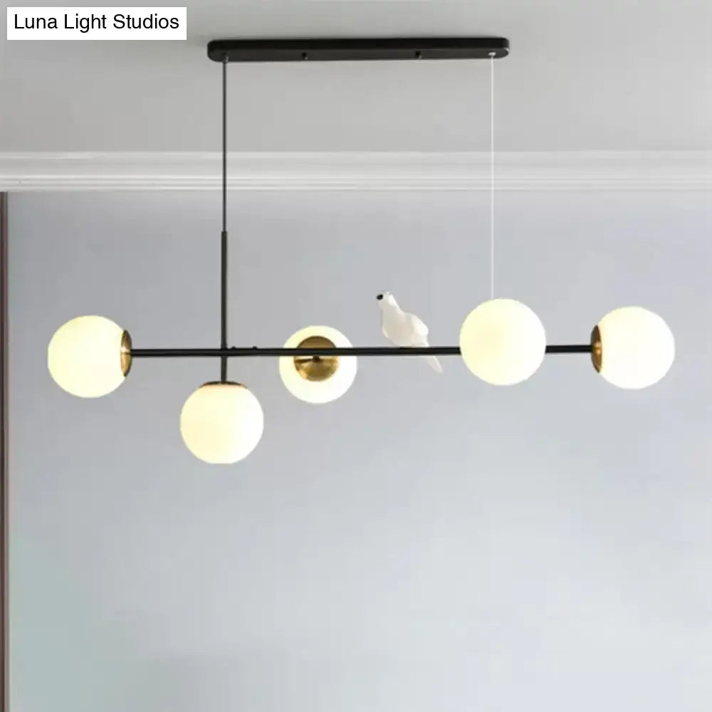 Modern DecorBites™ brass sphere pendant light with five frosted glass shades and adjustable cord for island pendant use