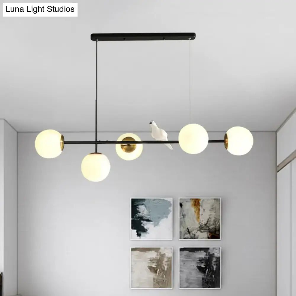 Modern black metal pendant light with five frosted glass shades and white ceramic bird on central bar island pendant