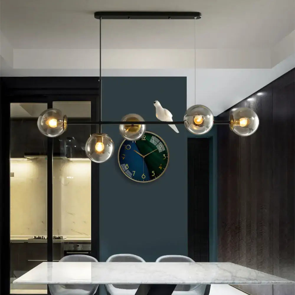 Decorbites™ brass sphere island pendant light with adjustable cord and amber glass shades with warm glowing bulbs