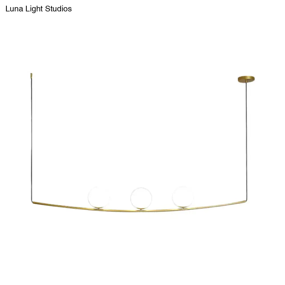 Gold-toned minimalist pendant light with three glass bulbs on a curved black gold metal frame for light bubble island use