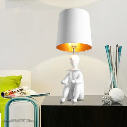 Modern black and gold ceramic clown desk lamp with white seated figurine base and orange interior shade decorbites clown desk