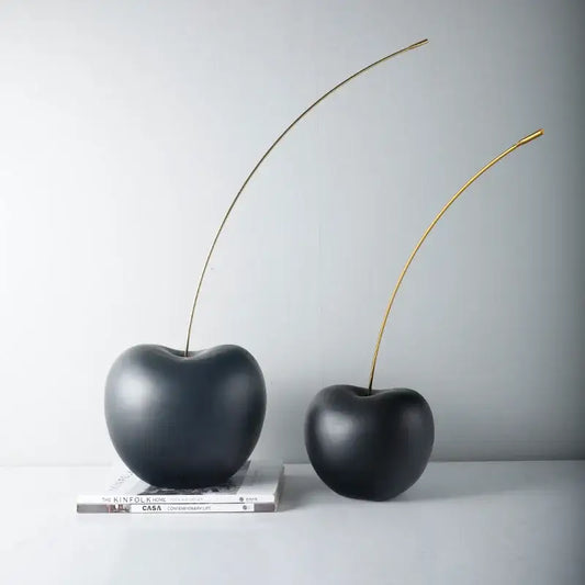 Two glossy black cherry resin sculptures with slender gold stems displayed on stacked books for modern decorbites decor