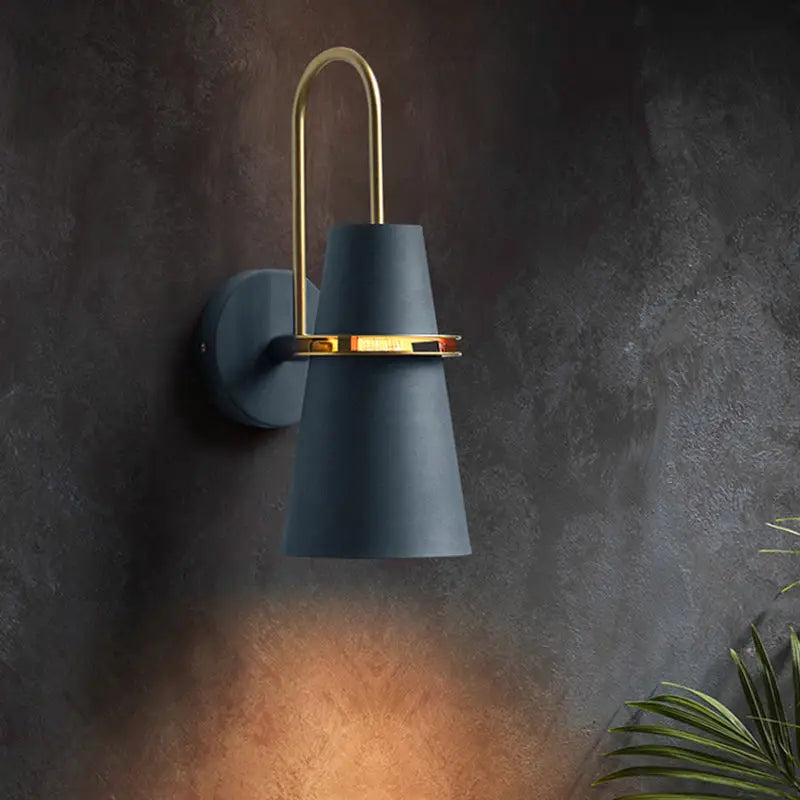 Modern wall sconce with matte navy blue conical shade and polished brass accents for dining room lighting
