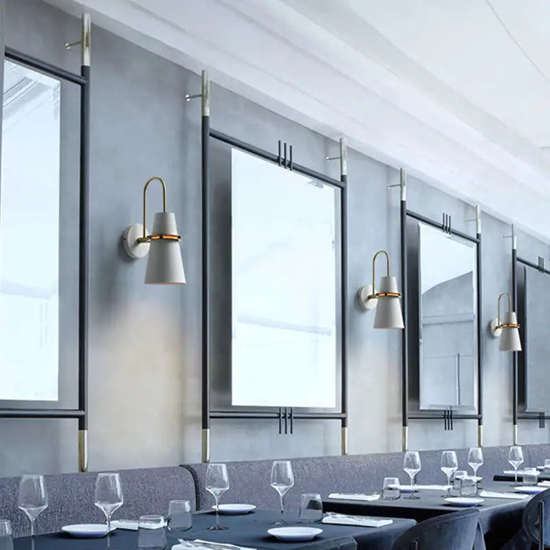 Modern black and gold conical sconce with gold metal arms and white shades on sleek black frames for dining room walls