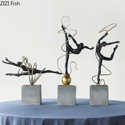 Set of three black metal decorbites gymnast figures with gold wire accents on gray concrete bases for living room decor