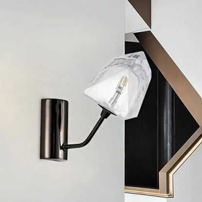 Modern black and gold wall sconce with faceted clear glass shade featuring bulb base and backplate width details