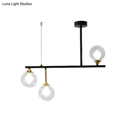 Modern black and brass DecorBites™ island chandelier with three clear glass ball shades for dining room lighting
