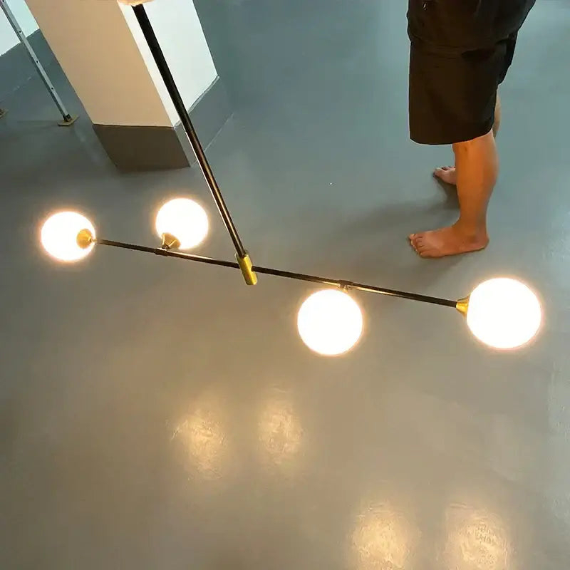 Modern black metal floor lamp with three glowing glass ball bulbs and gold-toned accents decorbites glass ball pendant