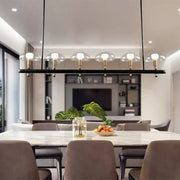 Modern black linear pendant light with five gold fixtures and clear glass shades for restaurant use by decorbites