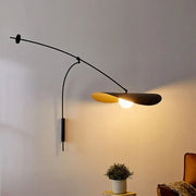 Modern black and gold leaf led wall lamp with glass shade and curved arm featuring warm golden interior for bedroom use