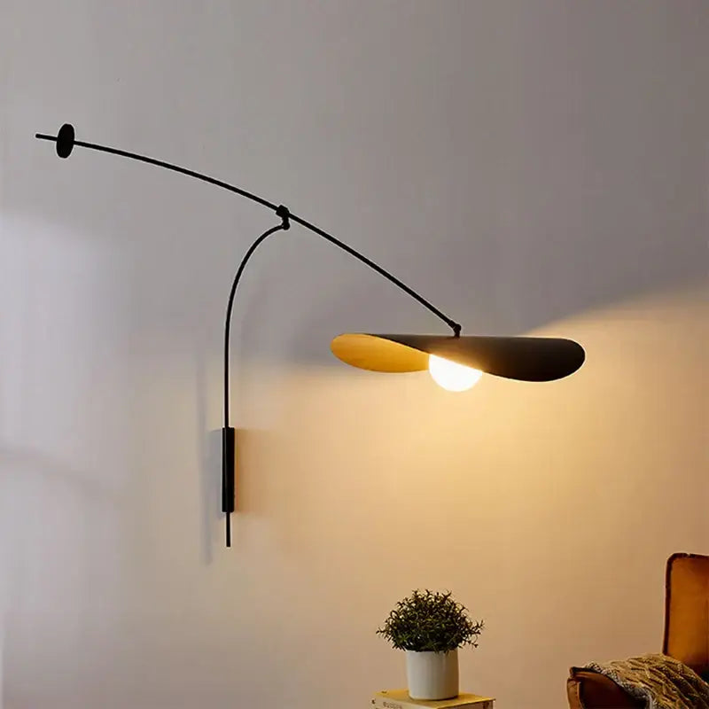 Modern black and gold leaf led wall lamp with glass shade and curved arm featuring warm golden interior for bedroom use