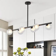 Modern black metal chandelier with five clear glass globe shades featuring light bulbs for dining table illumination