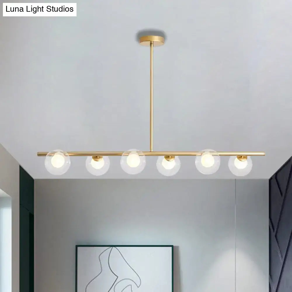 Gold-toned DecorBites™ modern pendant light with five clear glass globe light bulbs in a linear dining table design