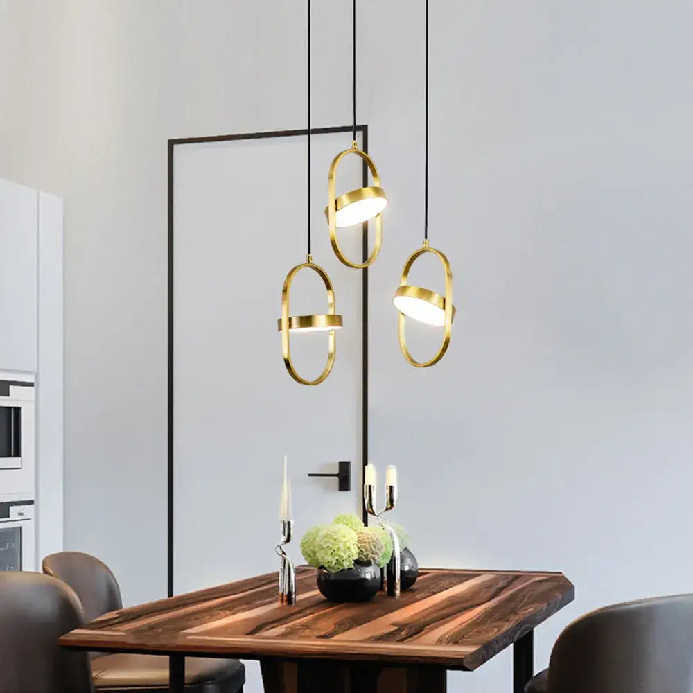 Three modern gold trumpet pendant lights with circular rings hang above a wooden dining table decorbites gold trumpet