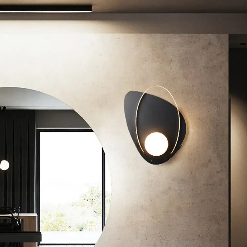 Modern black and gold wall lamp with oval white glass shade and glowing circular light for bedroom sconce