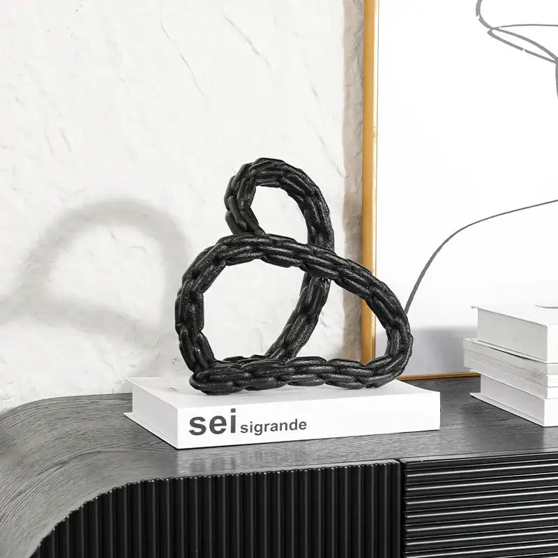 Modern black braided rope sculpture featuring a golden knot chain design for living room decor