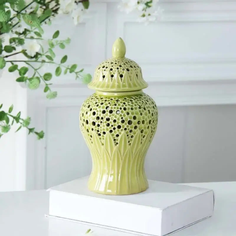 A pale green ceramic porcelain jar with intricate perforated patterns and leaf embossing for modern decor