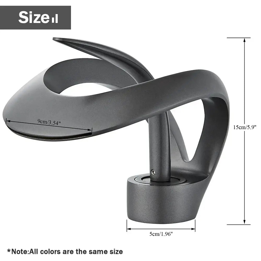 Matte black abstractly sculpted metal desk lamp next to a modern black and grey waterfall mixer tap basin faucet