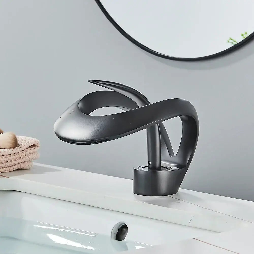 Modern black and grey waterfall mixer tap with matte finish and sleek sculptural design for bathroom basin faucet