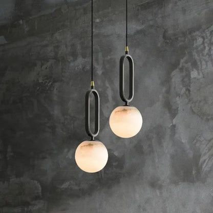 Modern pendant lights with matte black frames and warm frosted glass spheres featuring polished copper finish accents