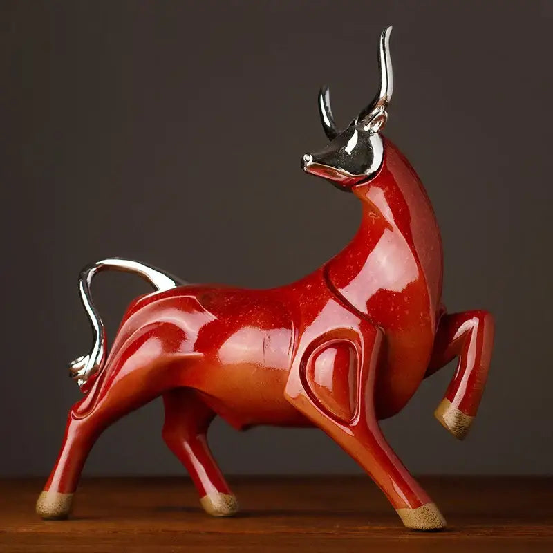 A glossy red ceramic decorbites bull sculpture with silver horns tail and hooves for modern living room decor