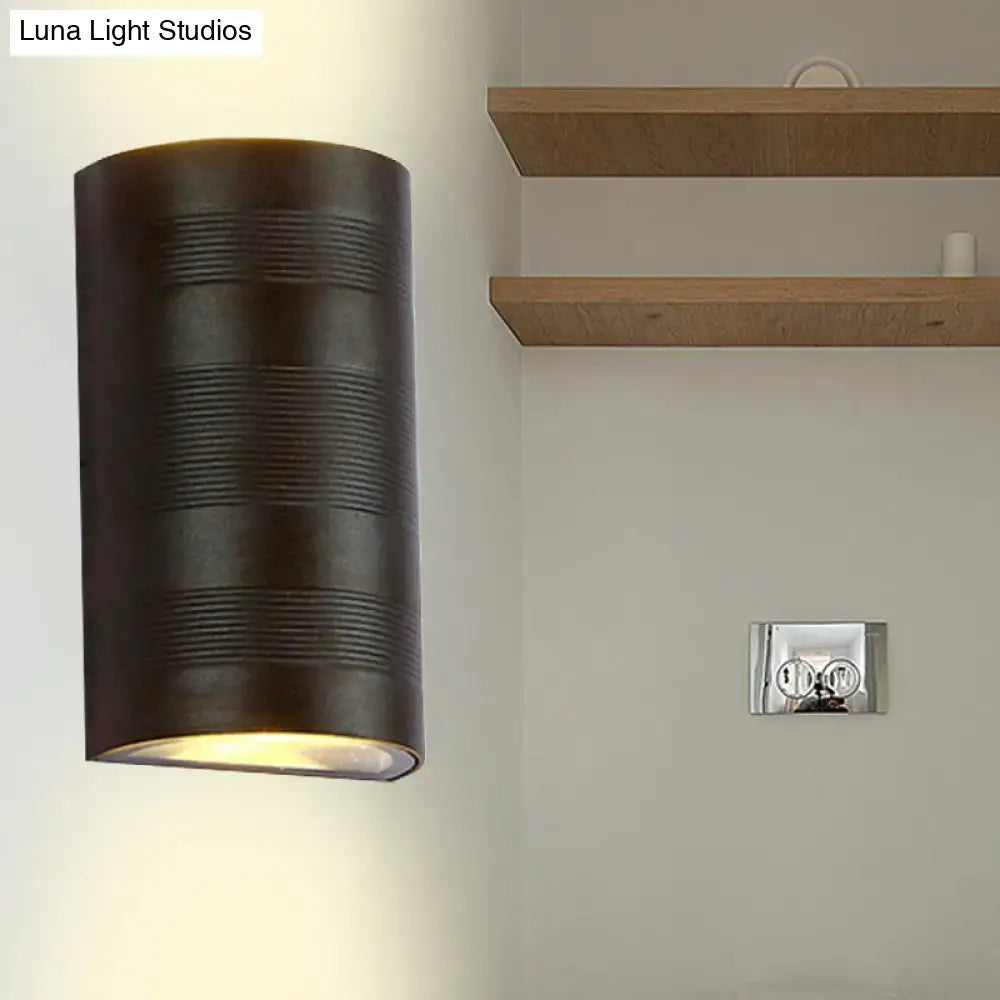 Dark bronze cylindrical wall lamp with horizontal ribbed texture and warm white diffused lighting for outdoor use