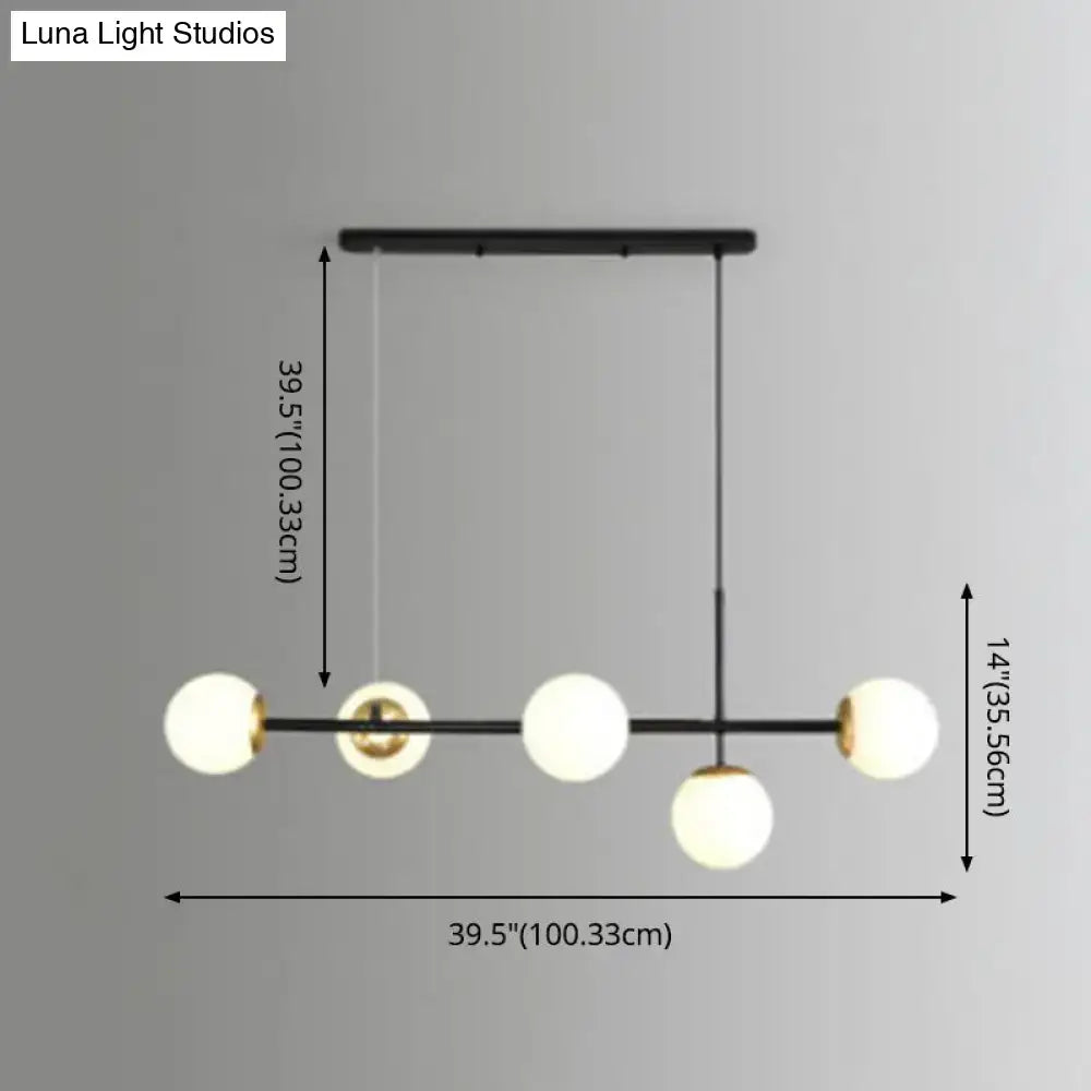 Modern black metal pendant light with five frosted glass shades and gold accents for linear island dining room use