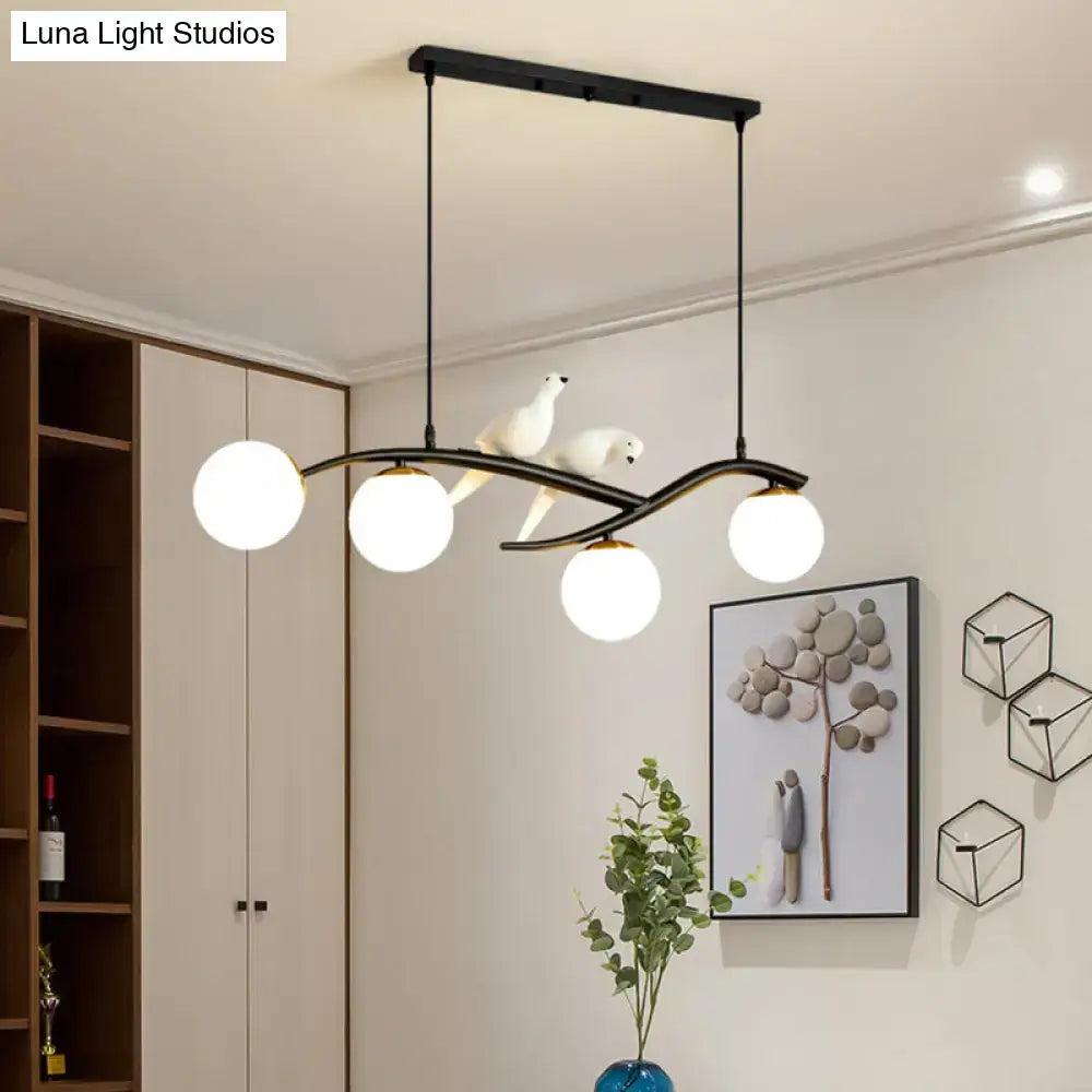 Modern black and white linear island pendant light with four glass shade bulbs and sculpted bird figures for dining room