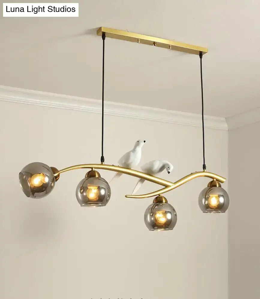Modern black and white bird linear island pendant light with gold-toned metal arm and three smoked glass shades