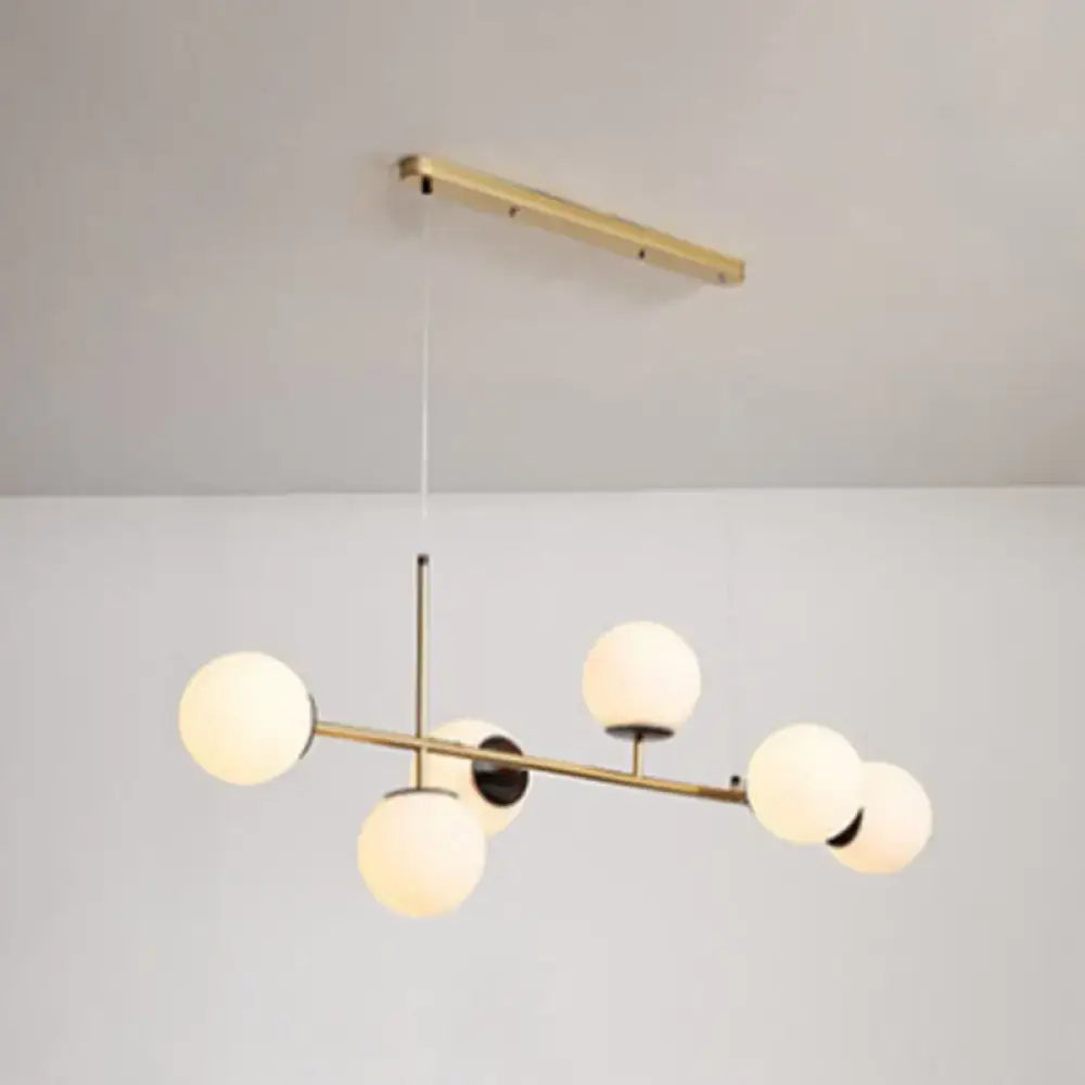 Modern black and white bird linear island pendant light featuring a brass fixture with five frosted glass shades