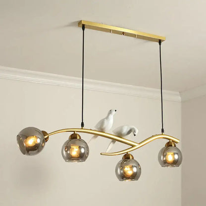 Modern black and white bird linear island pendant light with gold-toned frame and three spherical smoked glass shades