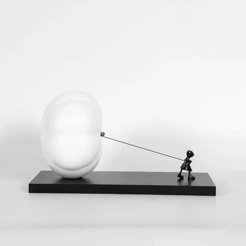 Modern black and white cartoon balloon man sculpture featuring a child figurine pulling a large white spherical balloon