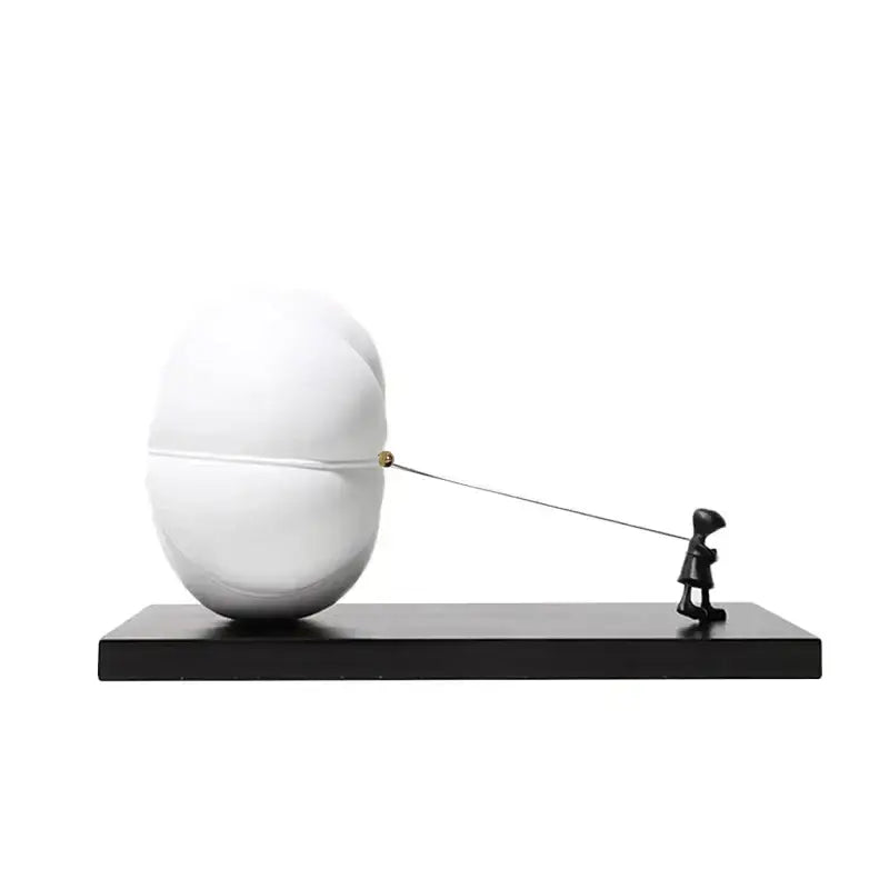 Modern black and white cartoon balloon man sculpture with white glossy egg shape and black figurine pulling string for decor