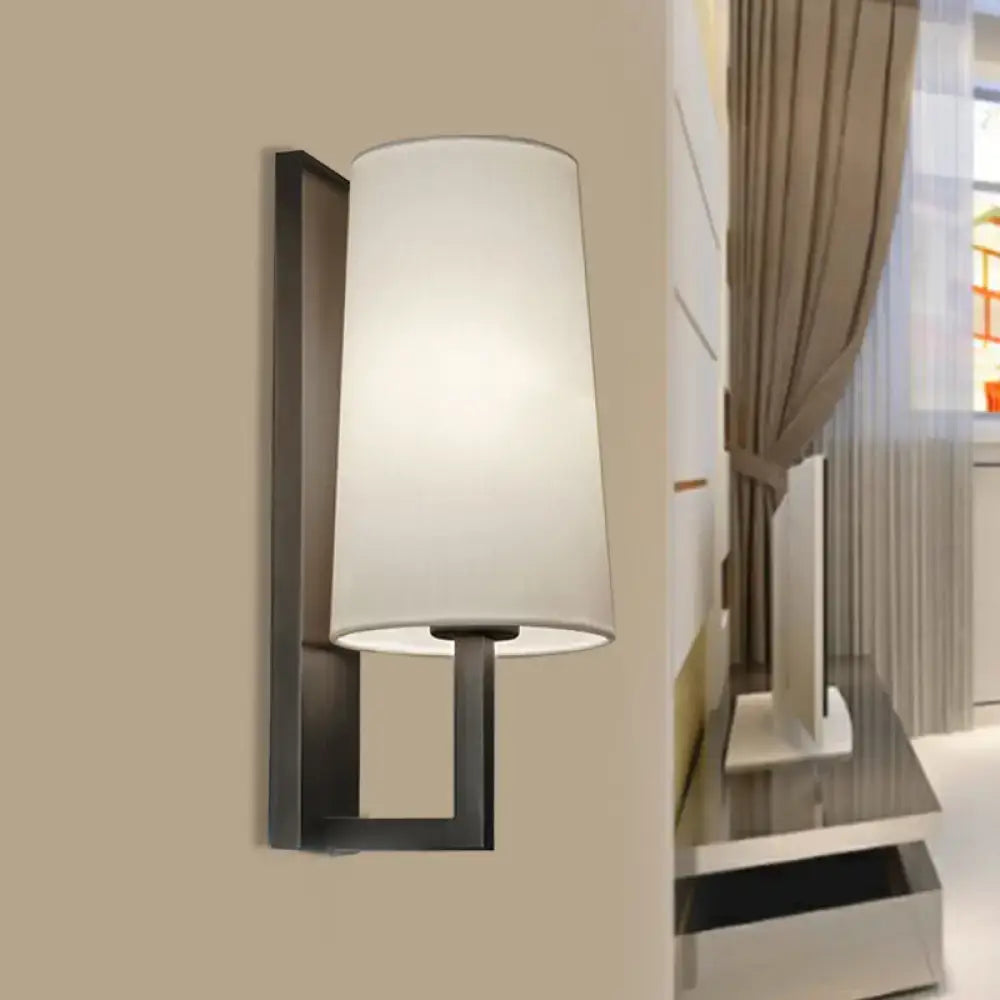 Modern black wall lamp with a cylindrical white fabric shade for bedroom lighting and contemporary decor
