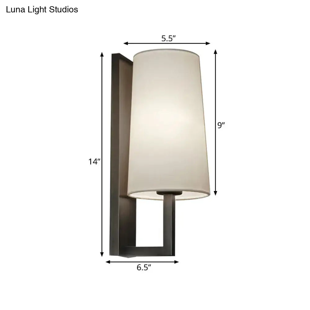 Modern black and white fabric wall lamp with matte black metal frame and off-white cylindrical shade for bedroom lighting