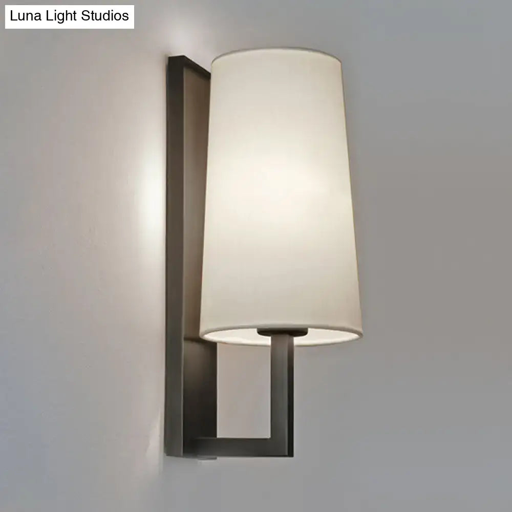 Modern black and white fabric wall lamp with matte black metal frame and off-white cylindrical shade for bedroom lighting