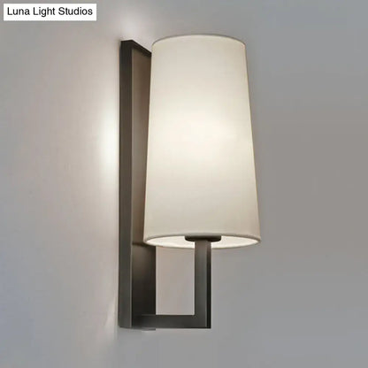 Modern black and white fabric wall lamp with matte black metal frame and off-white cylindrical shade for bedroom lighting