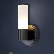 Modern black and white glass sconce lamp with cylinder white glass diffuser emitting warm bedroom wall light