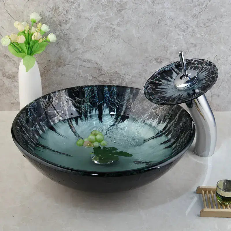 Modern black and white marble glass basin tap set with a black vessel sink featuring teal silver swirls and chrome waterfall tap set