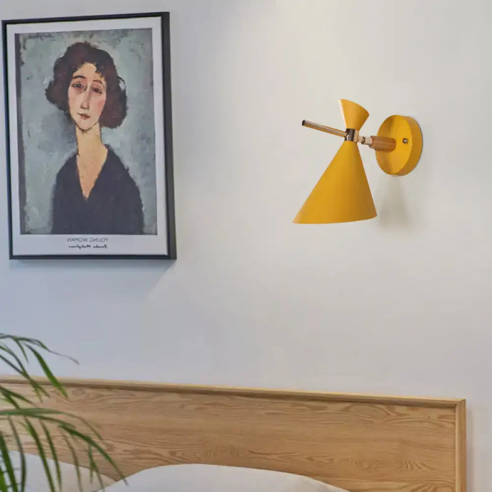 Yellow conical wall sconce with wooden arm and circular base featuring modern black angle shade for bedroom lighting