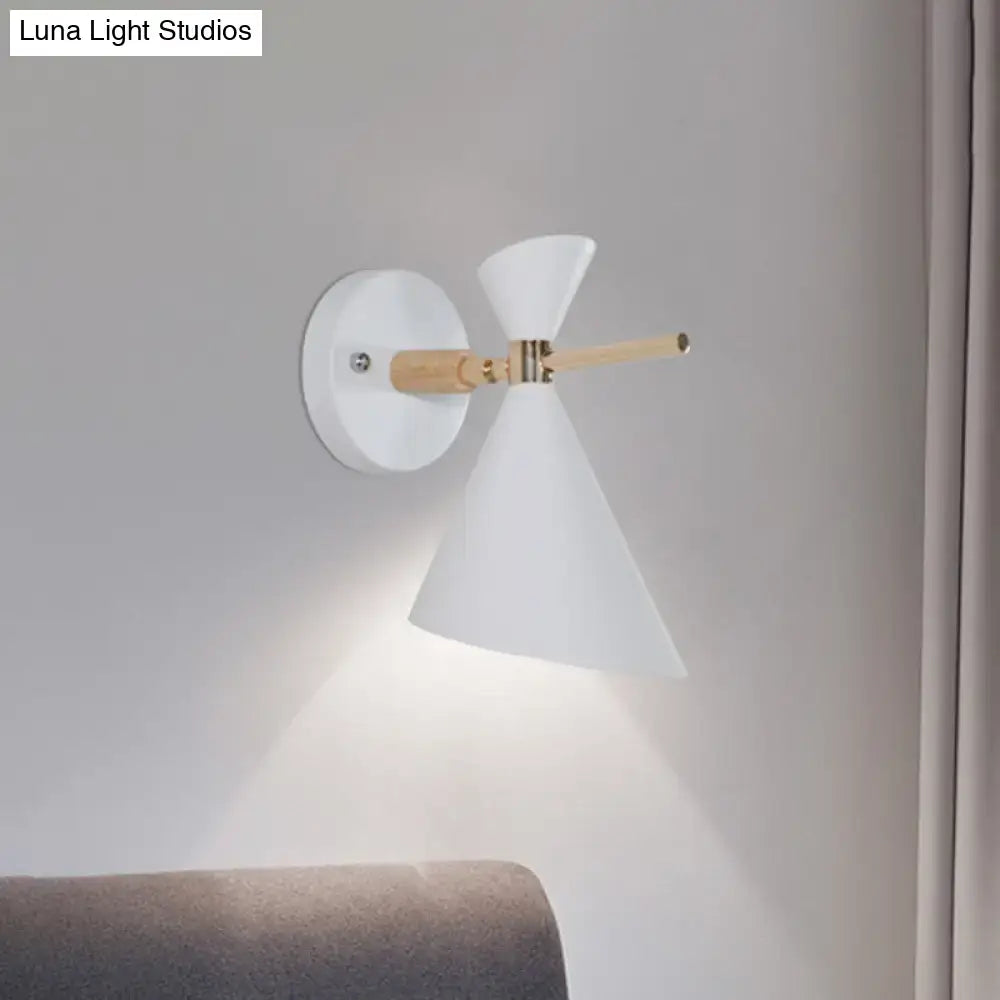 White conical wall sconce with natural wood arm and brass accents featuring modern black angle shade for bedroom lighting