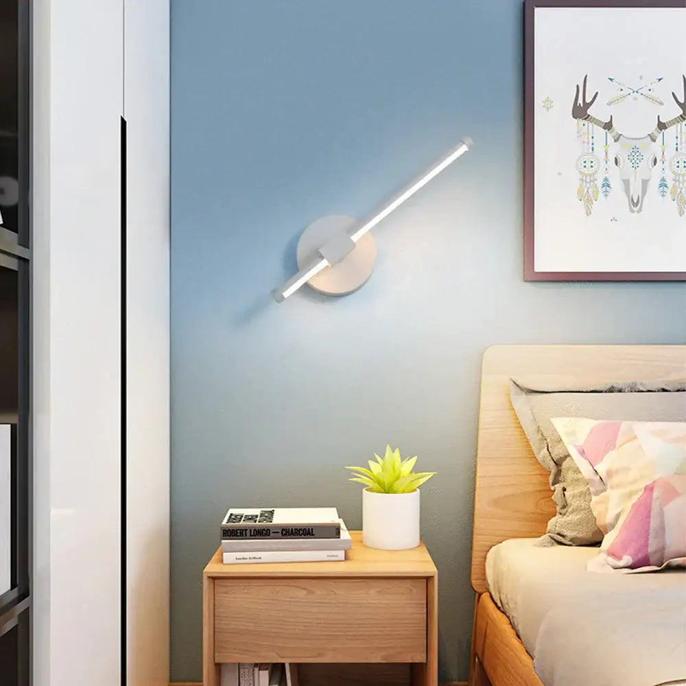 Modern black angular indoor led wall light with sleek white circular base and slender angled light bar for bedroom decorbites indoor led