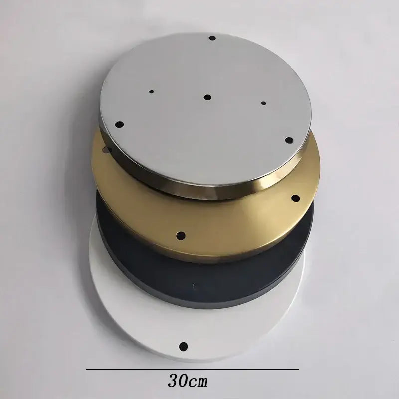 Stacked circular metal base plate lighting accessories in silver gold black and white with evenly spaced perimeter holes