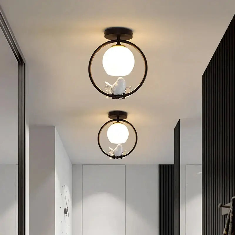 Modern black bird ceiling light fixture with white spherical bulb and delicate bird figurine for corridor entrance
