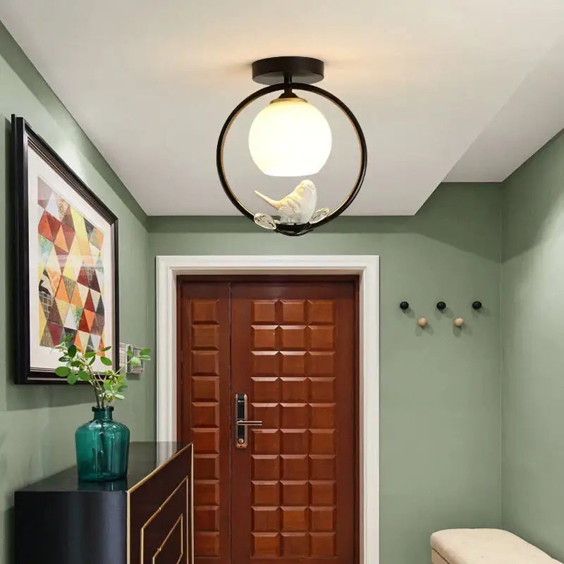 Modern black ceiling light fixture with frosted glass globe and white bird figurine for corridor entrance lighting