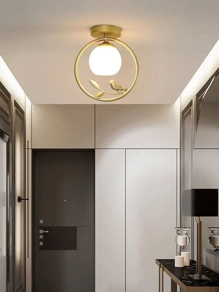 Modern black bird ceiling light fixture with gold-toned circular frame and ornamental bird design for corridor entrance