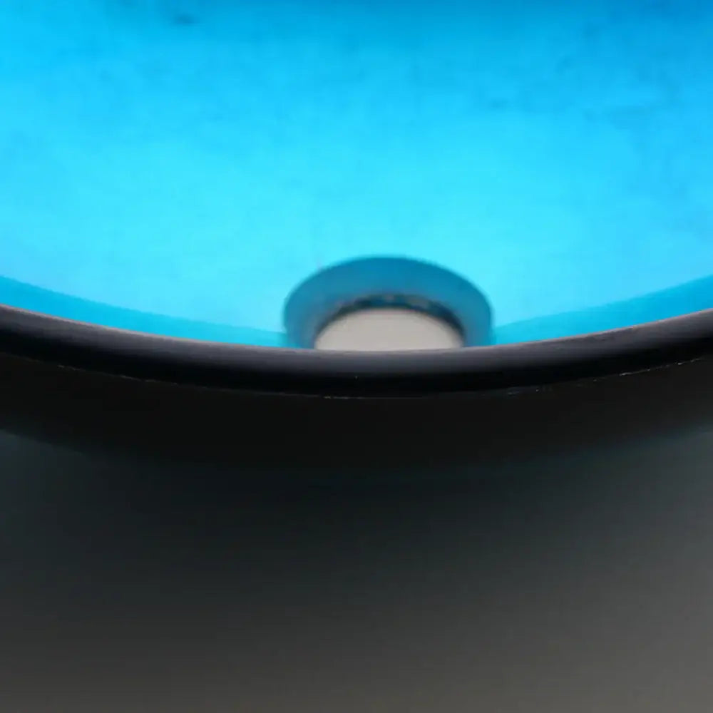 Modern black and blue glass vessel sink basin tap set with a blue ceramic sink, black rim, and metallic drain