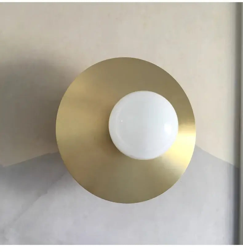 Modern black and brass glass ball light fixture wall sconce with minimalist brass circular base and white globe bulb decorbites golden glass
