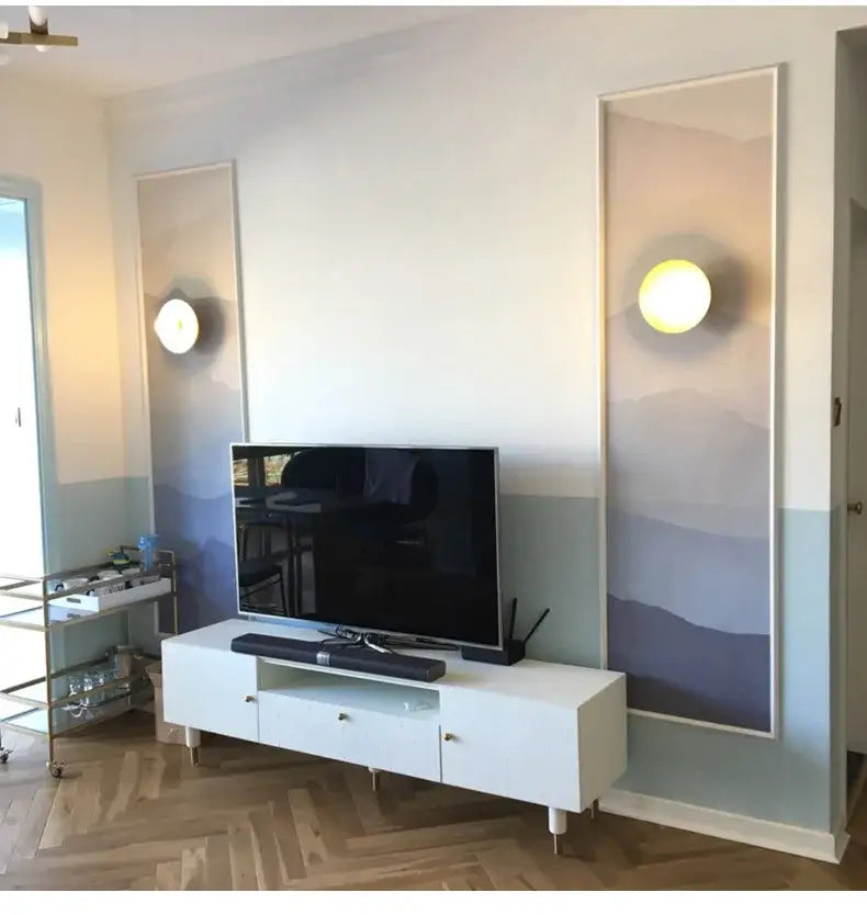 White minimalist tv stand with glass drawer fronts and sleek legs featured beside decorbites golden glass wall sconce light fixture