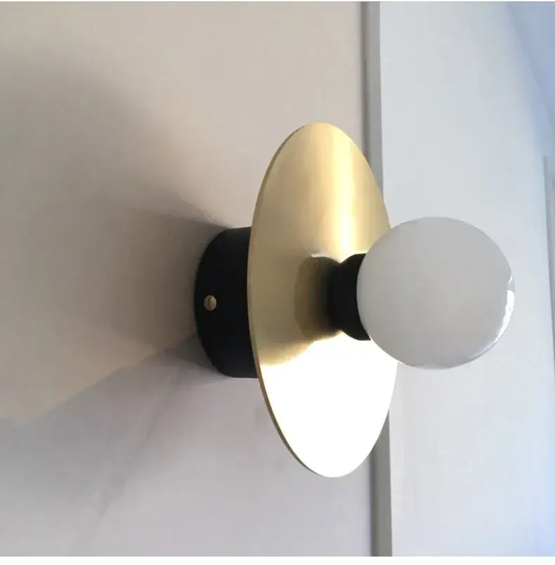 Modern black and brass glass ball light fixture wall sconce with sleek base gold-toned disc and frosted glass bulb decorbites golden glass
